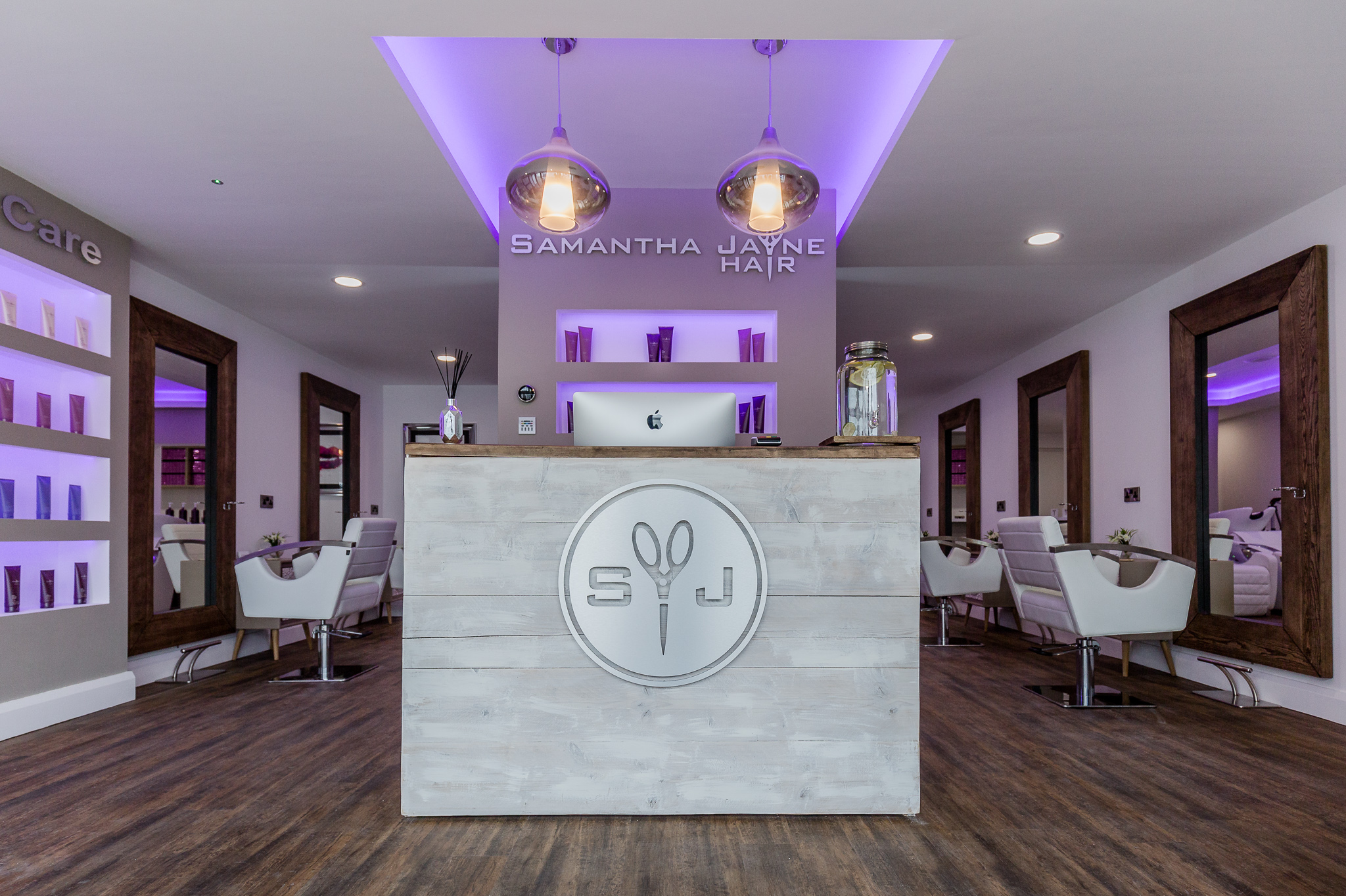 Inside the salon: the reception desk, styling chairs, tall wooden mirrors and lilac lighting