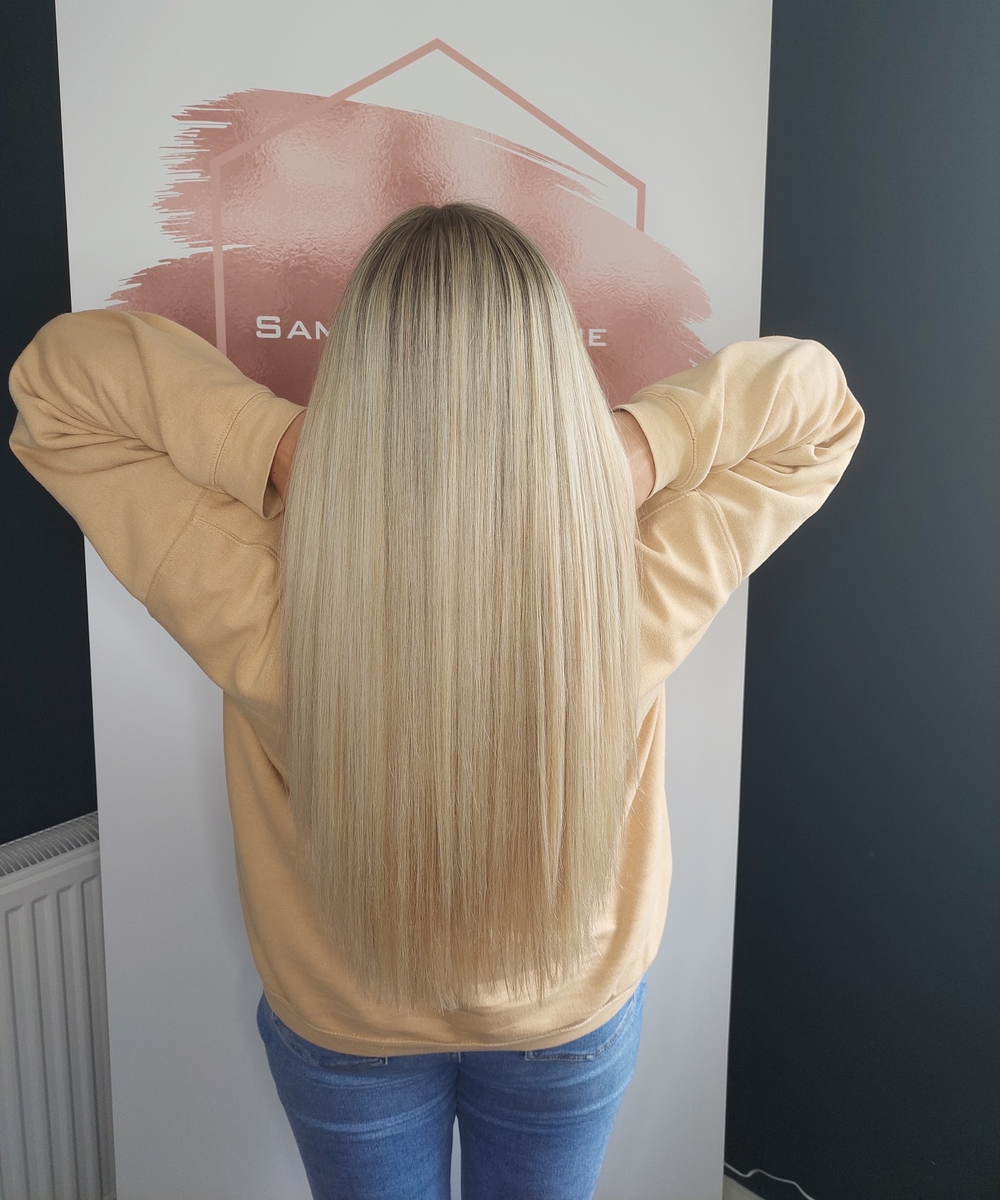 Long, straight, bright blonde hair in front of the salon banner