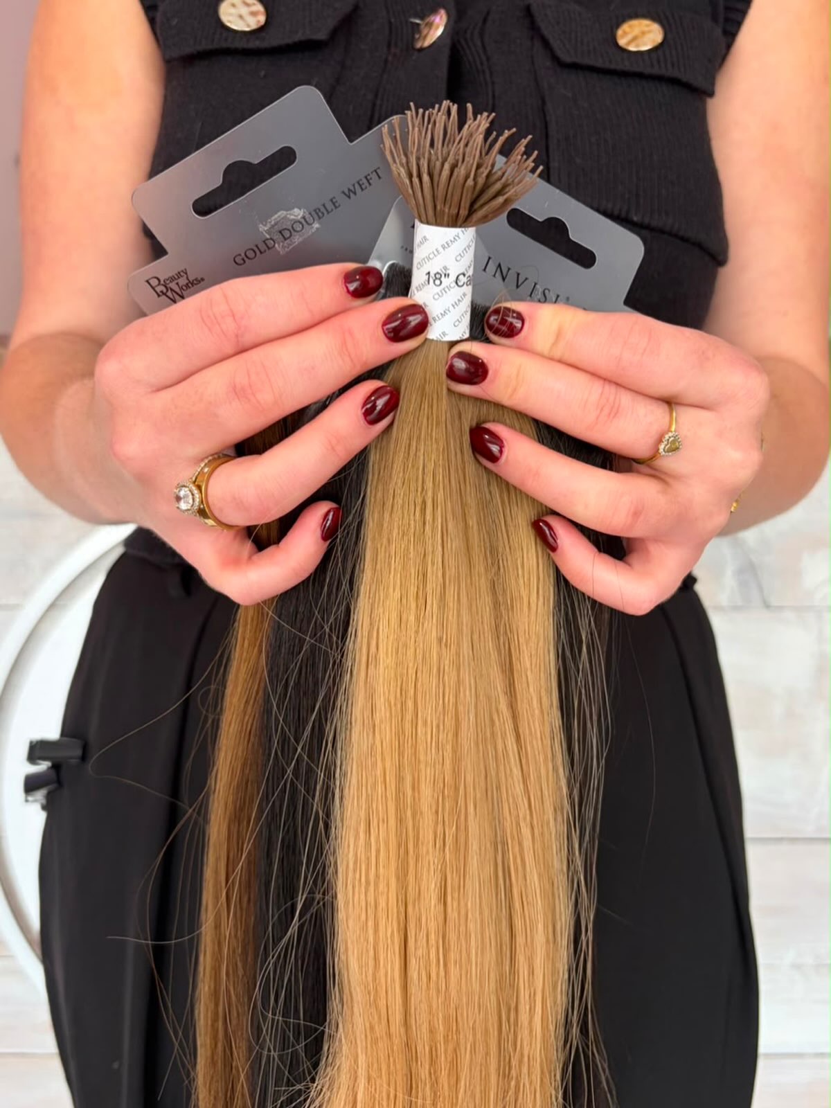 A stylist holding a pack of extension hair in a golden blonde shade