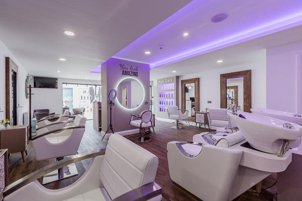 Wash basins and styling chairs under lilac lighting